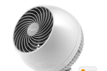 “White IRIS USA WOOZOO Oscillating Fan on a desk with remote control, providing quiet airflow in a home office.”