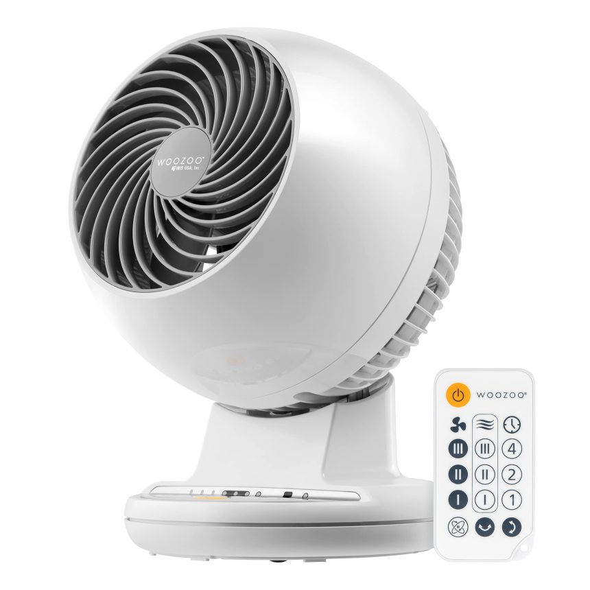 “White IRIS USA WOOZOO Oscillating Fan on a desk with remote control, providing quiet airflow in a home office.”