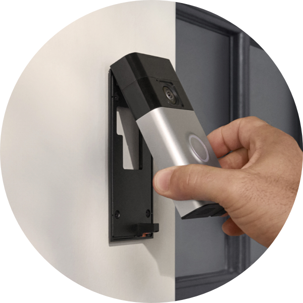A hand attaches Ring Battery Doorbell to a mount installed next to a front door.
