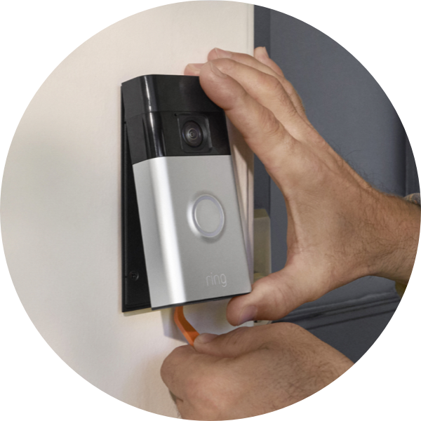 A pair of hands use a removal tool to detach Ring Battery Doorbell from a wall mount.
